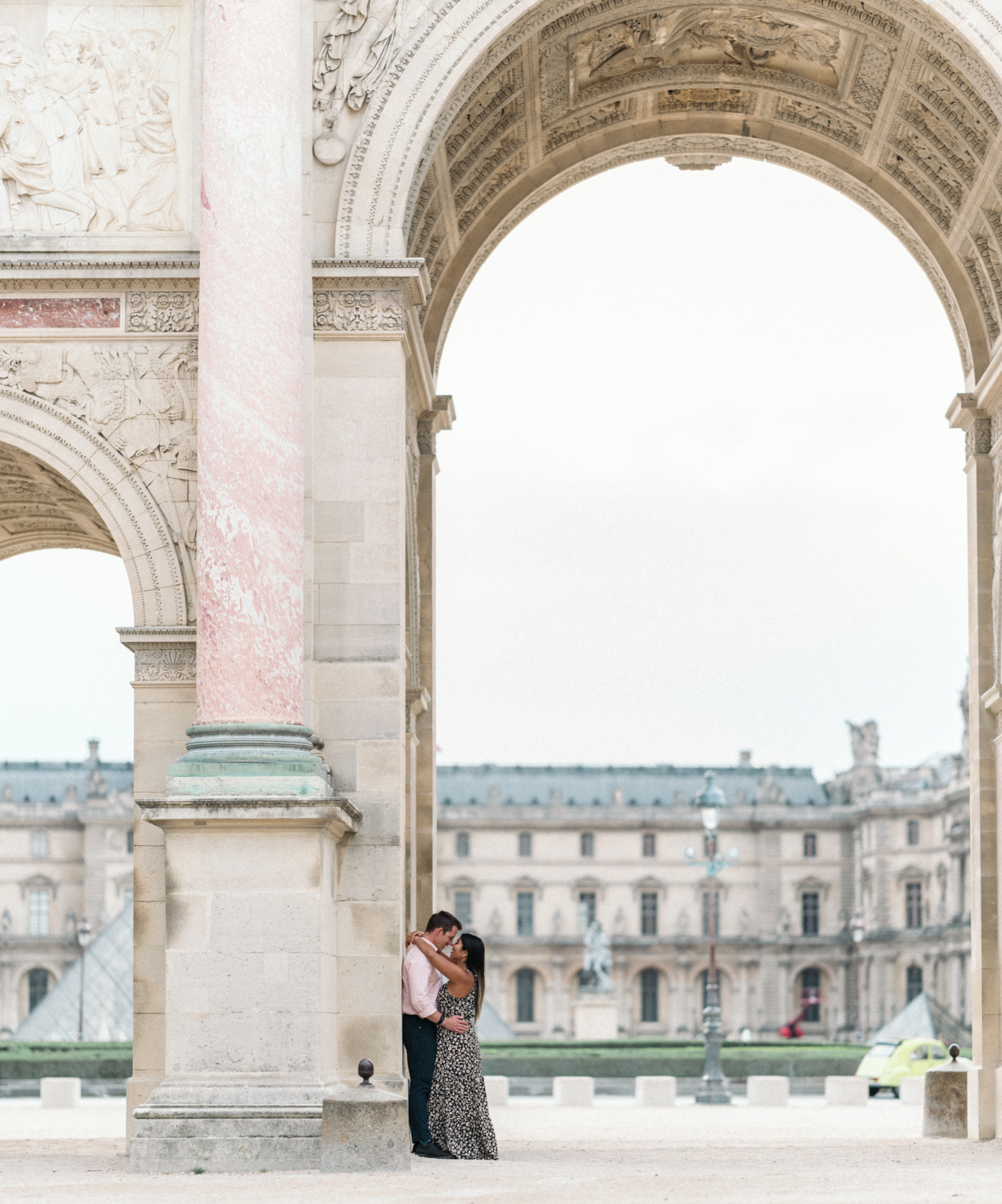 newly engaged couple hold each other with view of louvre in background in paris france