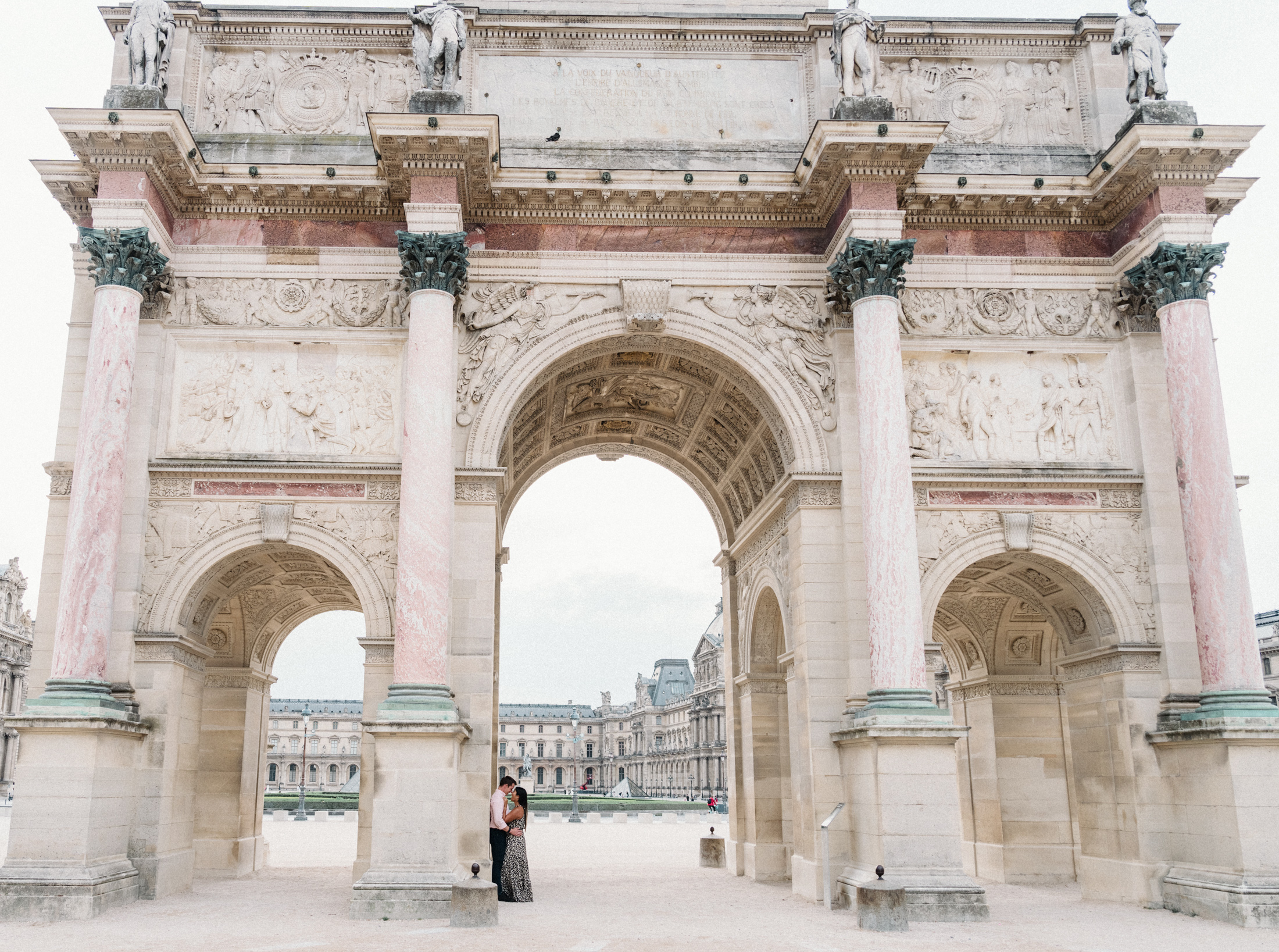 newly engaged couple embrace with louvre in background in paris france