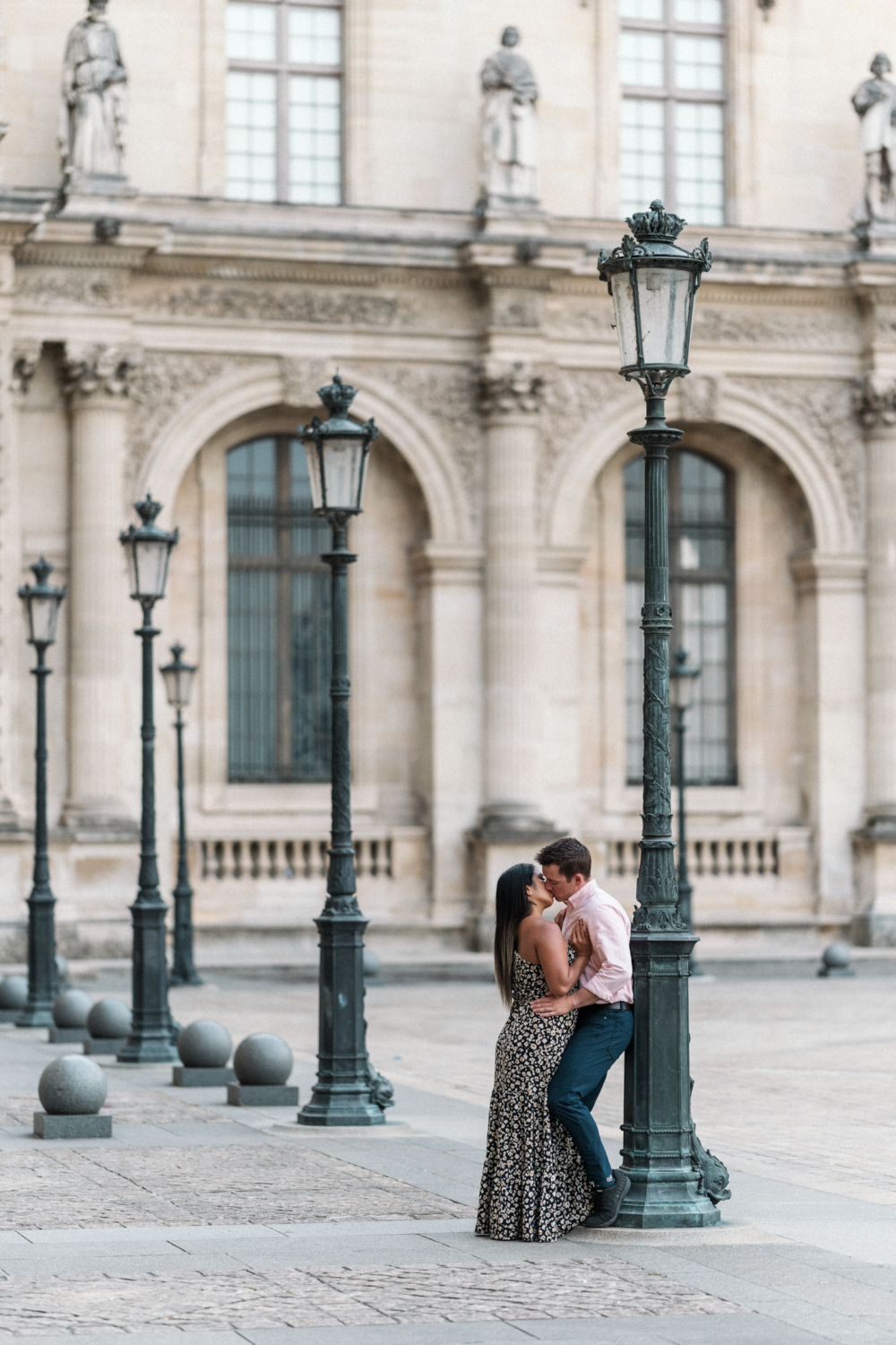 newly engaged couple kiss in the courtyard of the louvre in paris