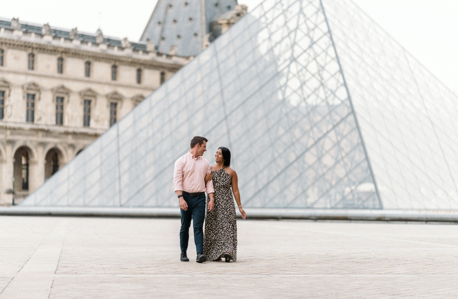 newly engaged couple walk arm in arm at louvre museum in paris france