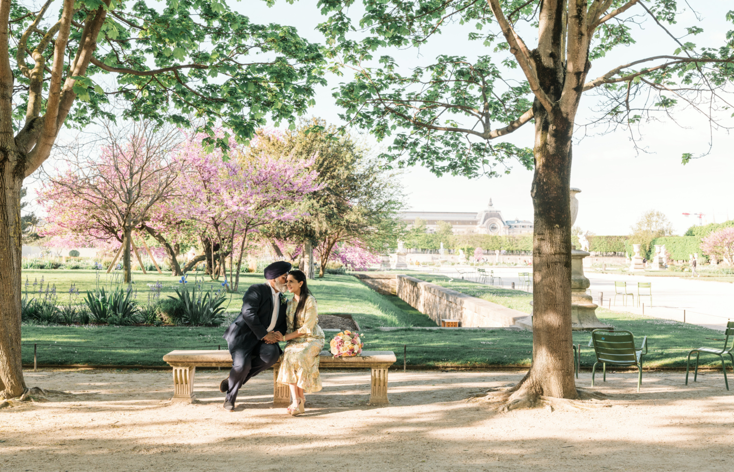 indian man kisses wife on cheek in flowering garden in paris