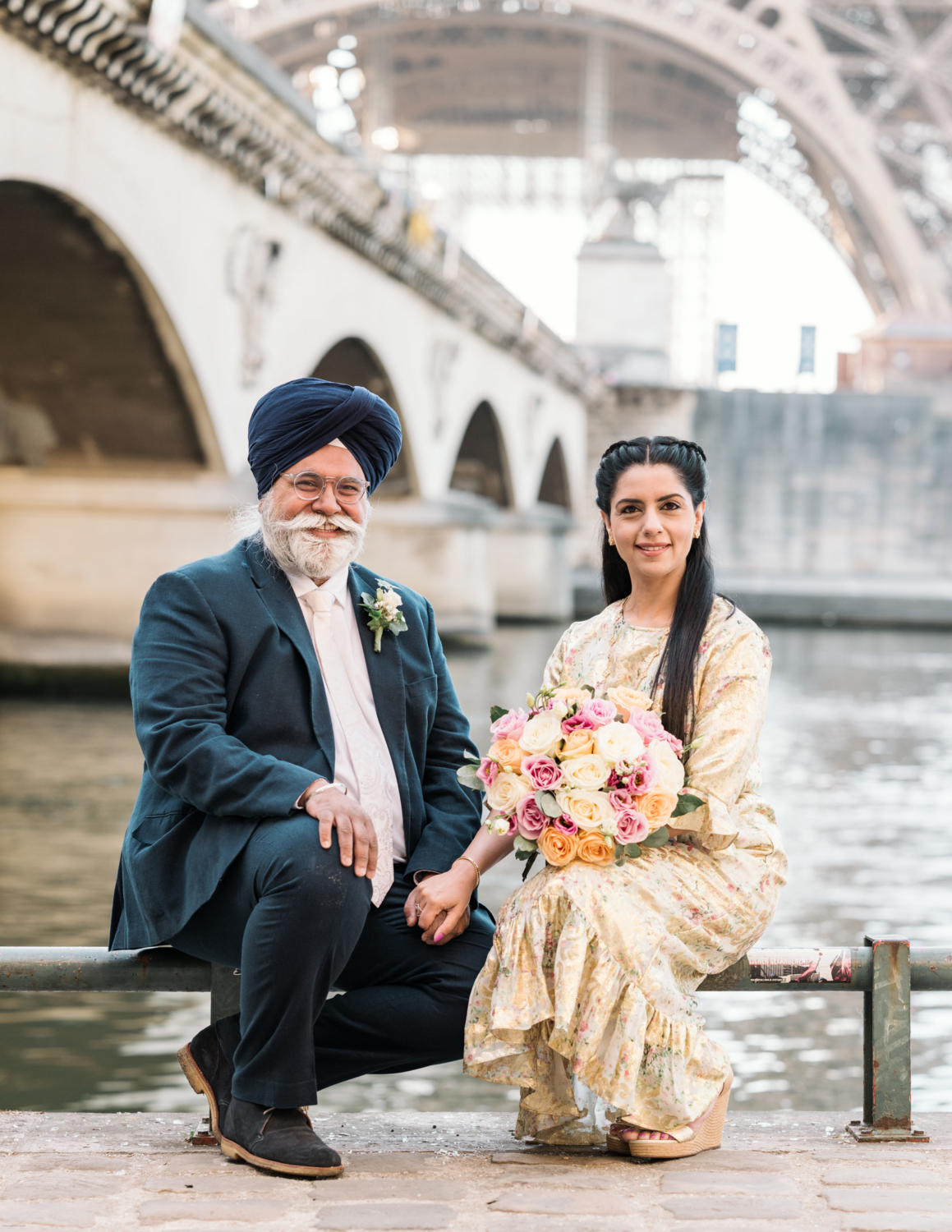 mature indian couple hold hands and smile in paris with under the eiffel tower