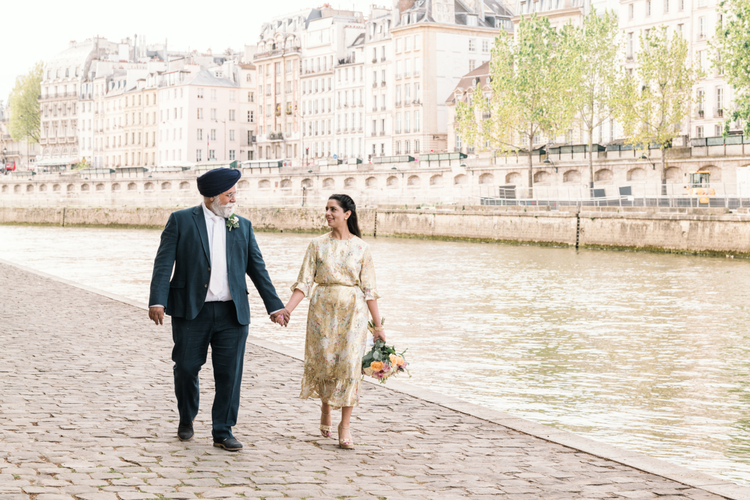 mature indian couple smile as they walk along the river in paris france