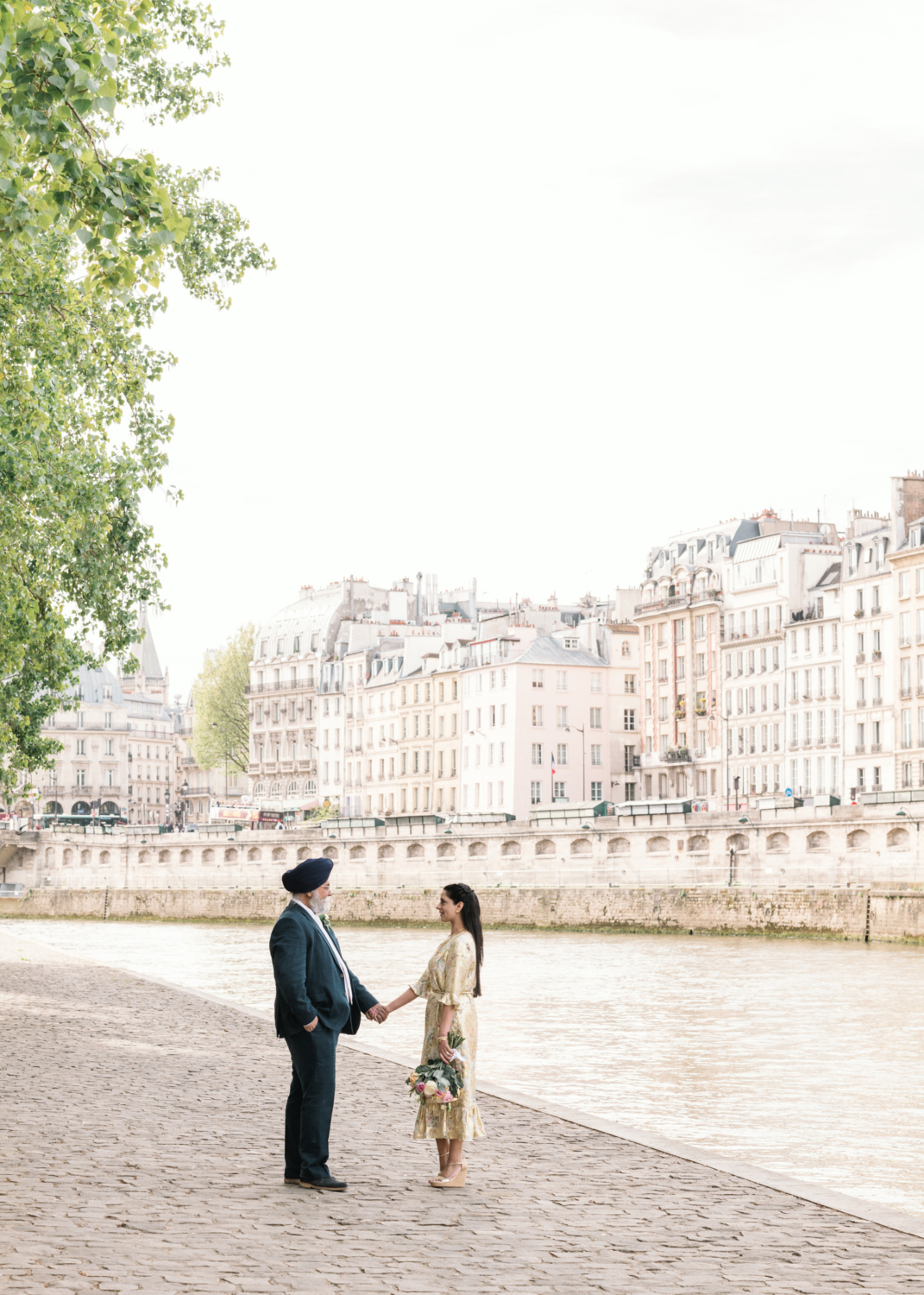 mature indian couple face each other holding hands at the seine river in paris