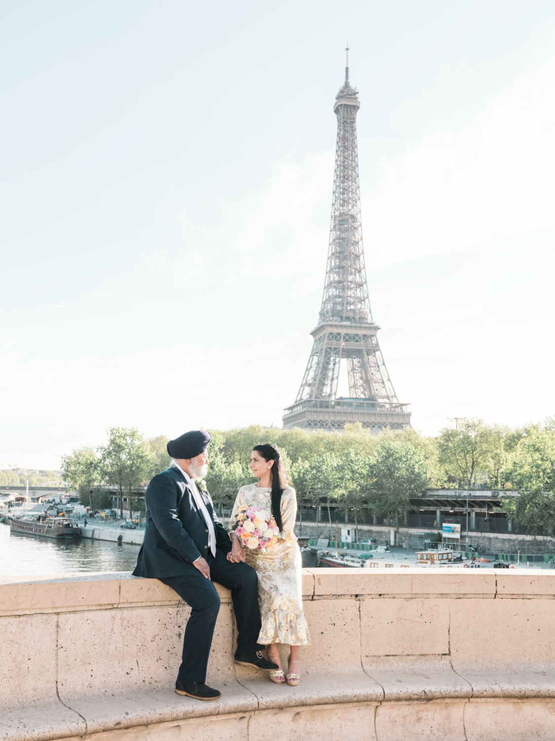 mature indian couple pose with view of eiffel tower in background in paris