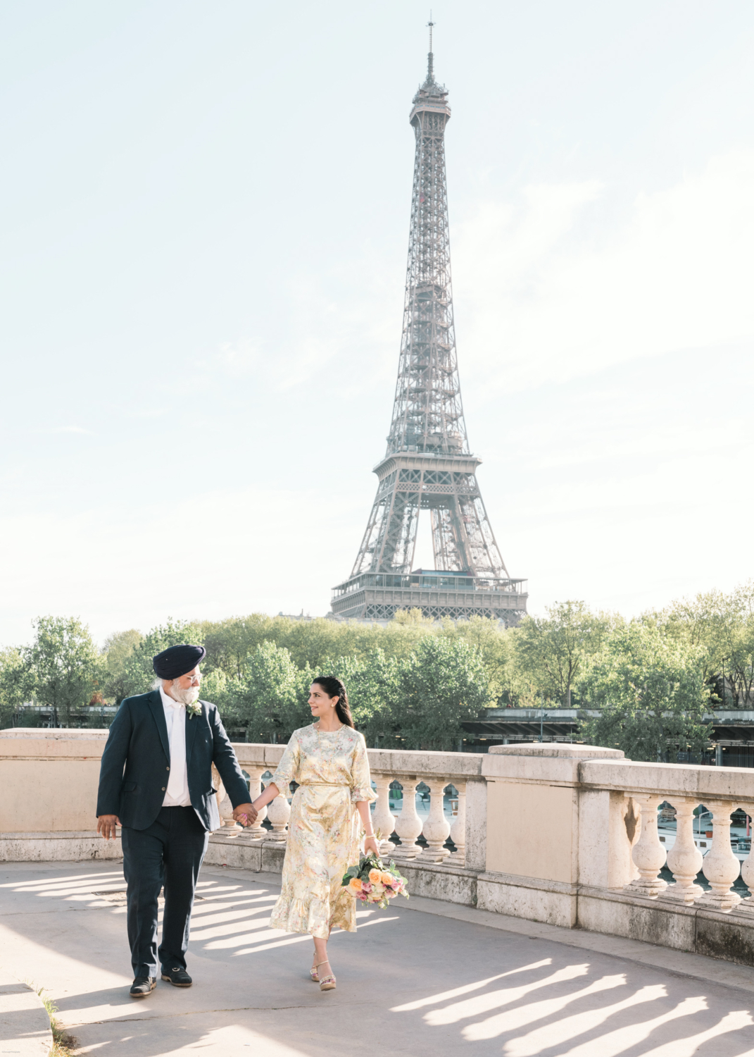 mature indian couple hold hands in paris with eiffel tower behind them