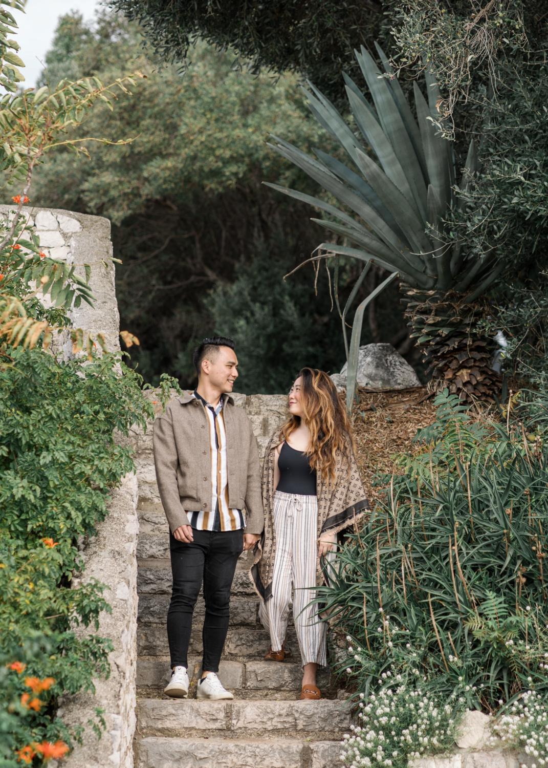 cute newly engaged couple walk through garden in nice, france