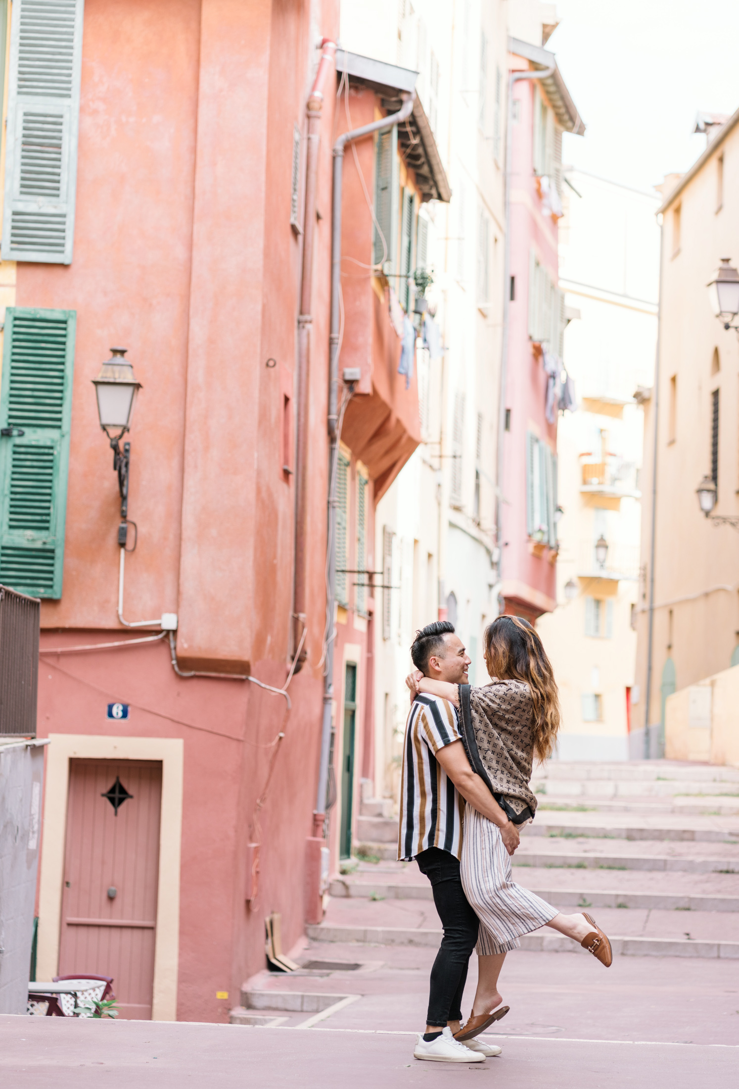 newly engaged man lifts woman in colorful old town nice france