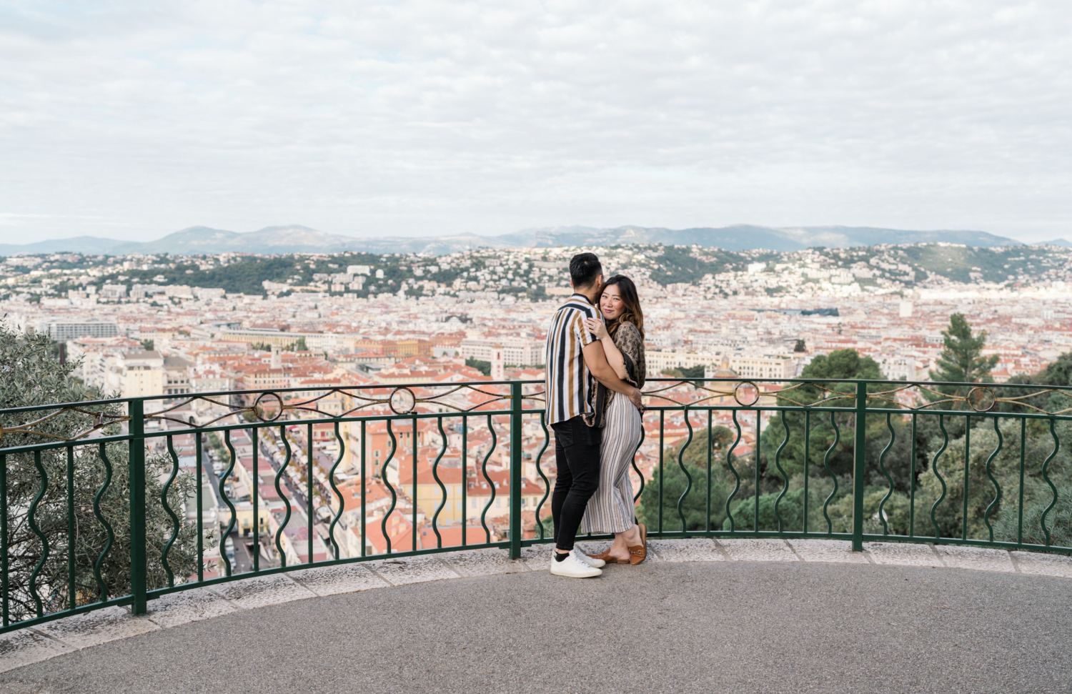 newly engaged couple embrace with view of nice in france