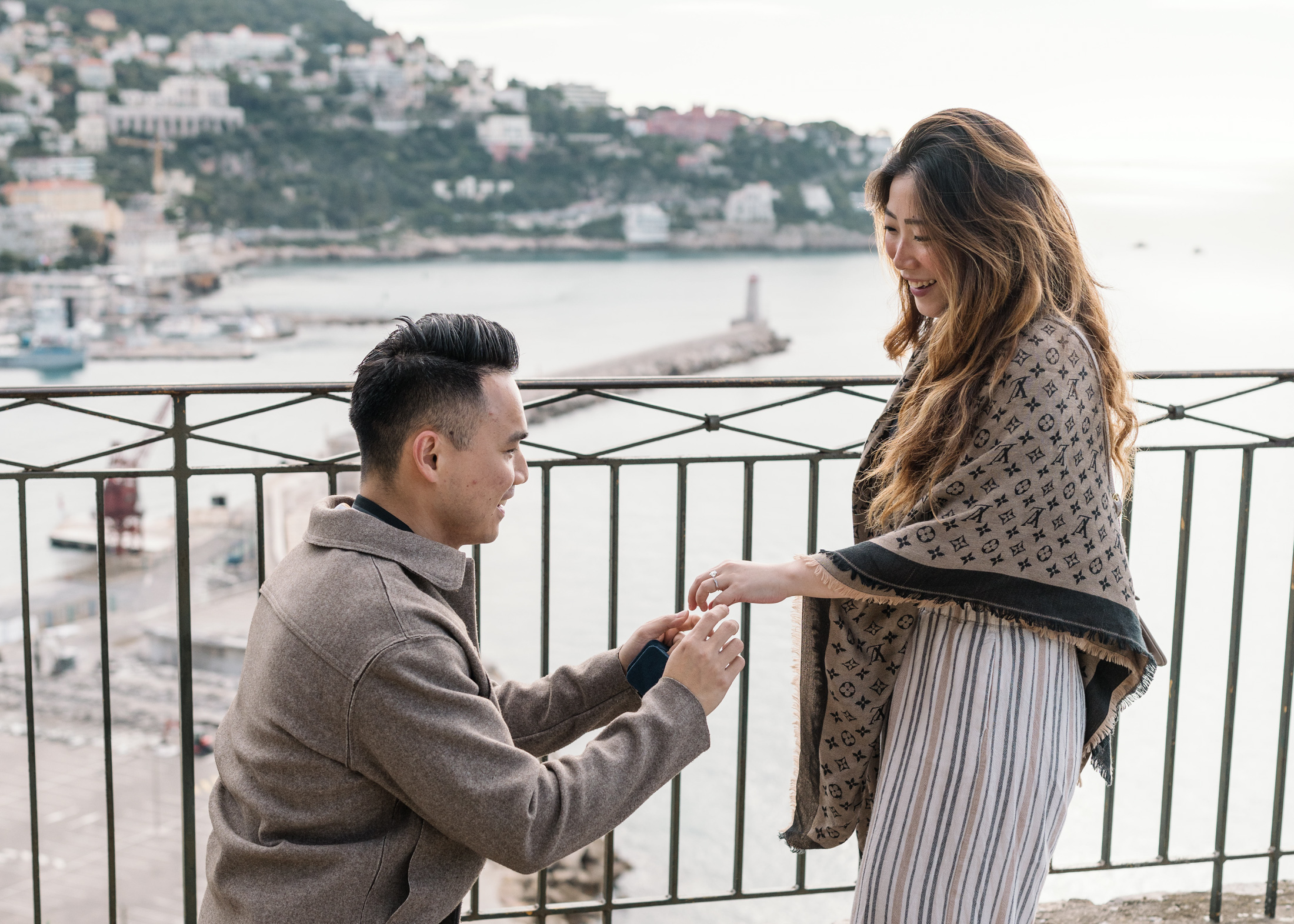 man slips engagement ring on woman's finger castle hill nice france