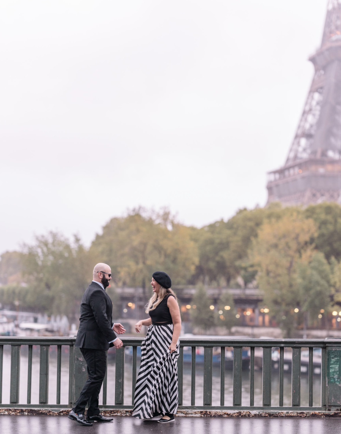 cute woman in beret laughs with husband with view of eiffel tower