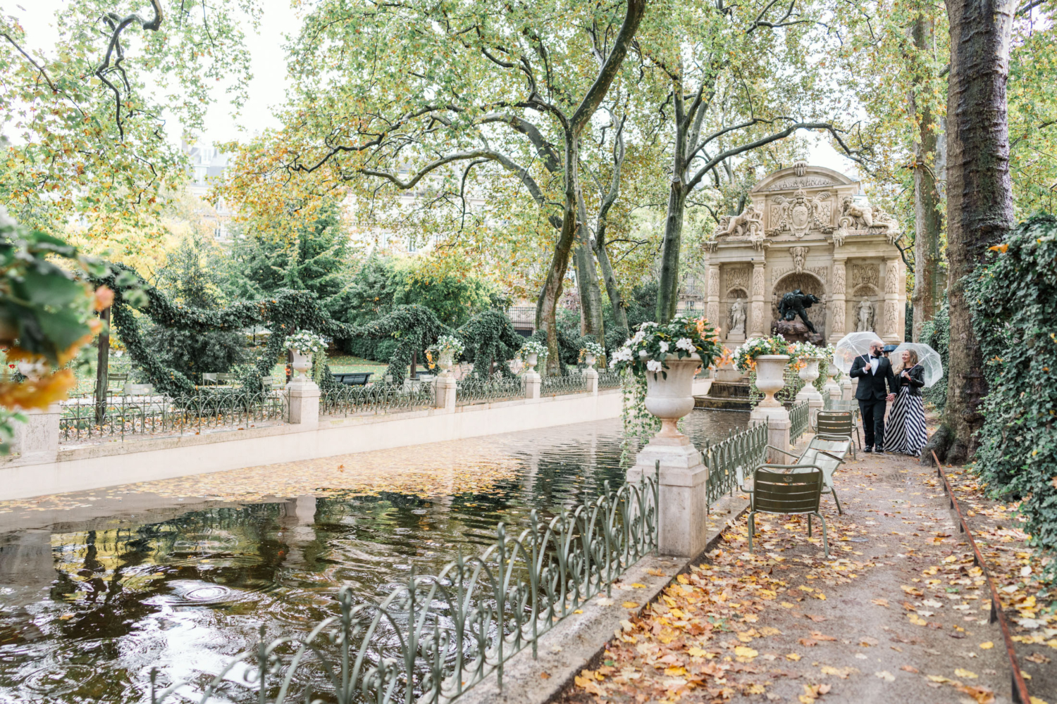 happy mature couple walk in the rain in luxembourg gardens paris