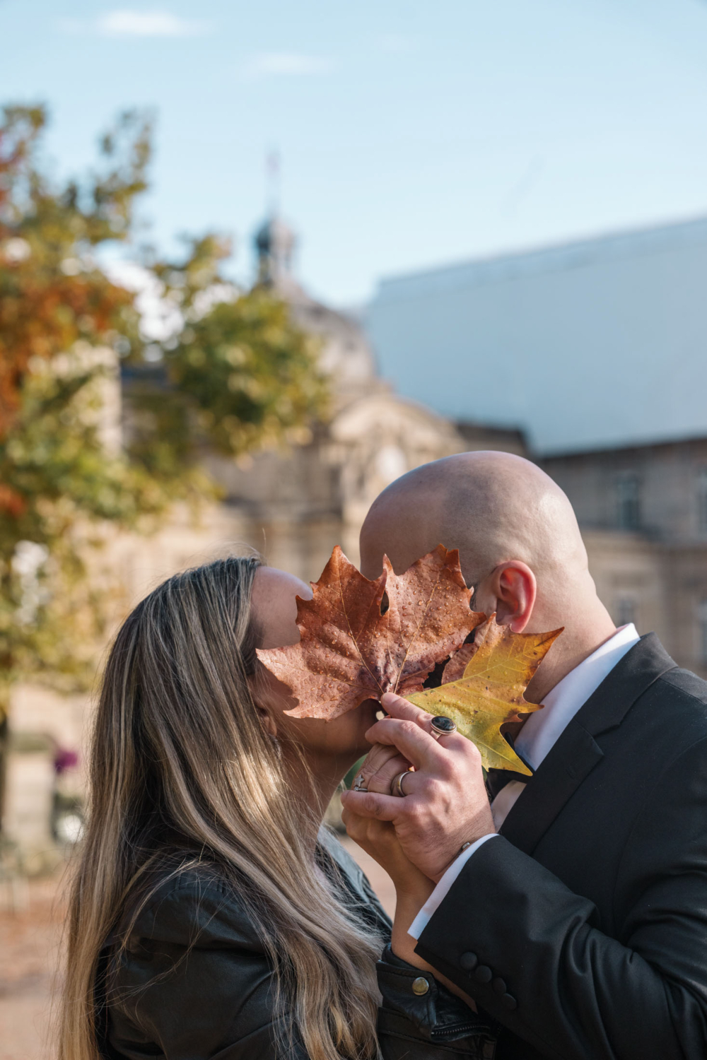 mature couple kiss behind autumn leaf in paris france