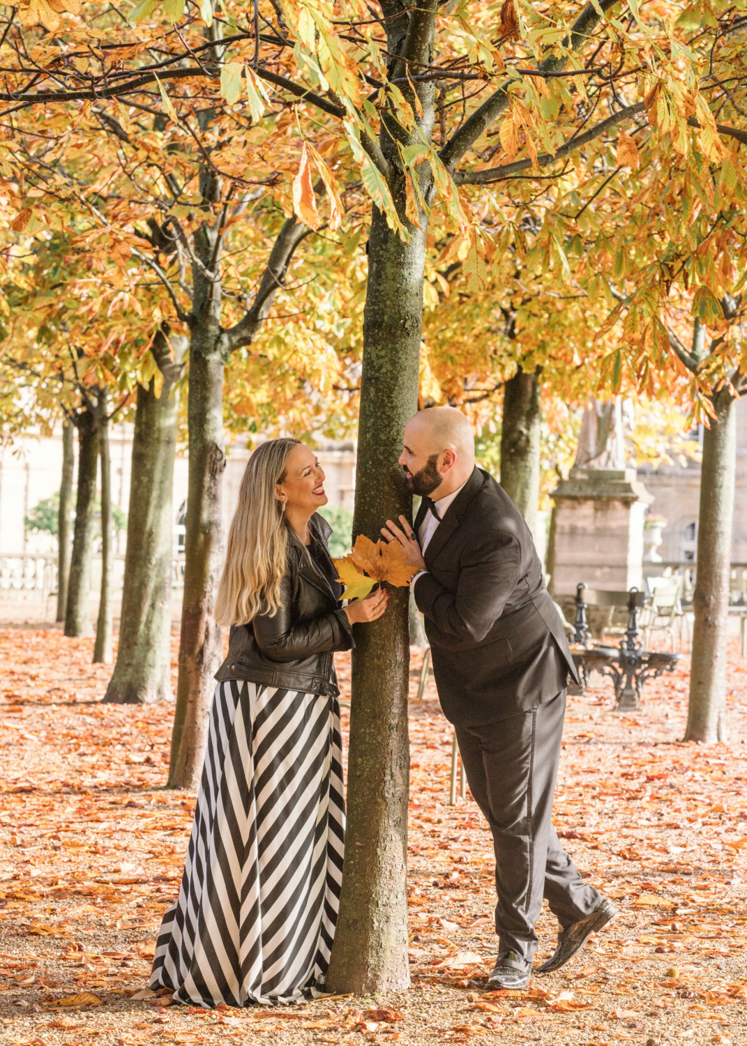 cute married couple play with the autumn leaves in luxembourg gardens in paris