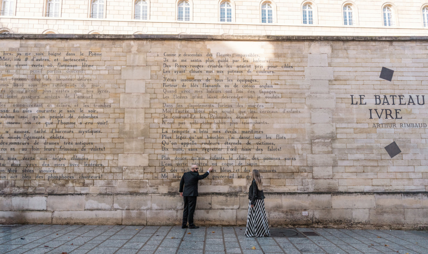 man points to poetry on le bateau ivre wall in paris france