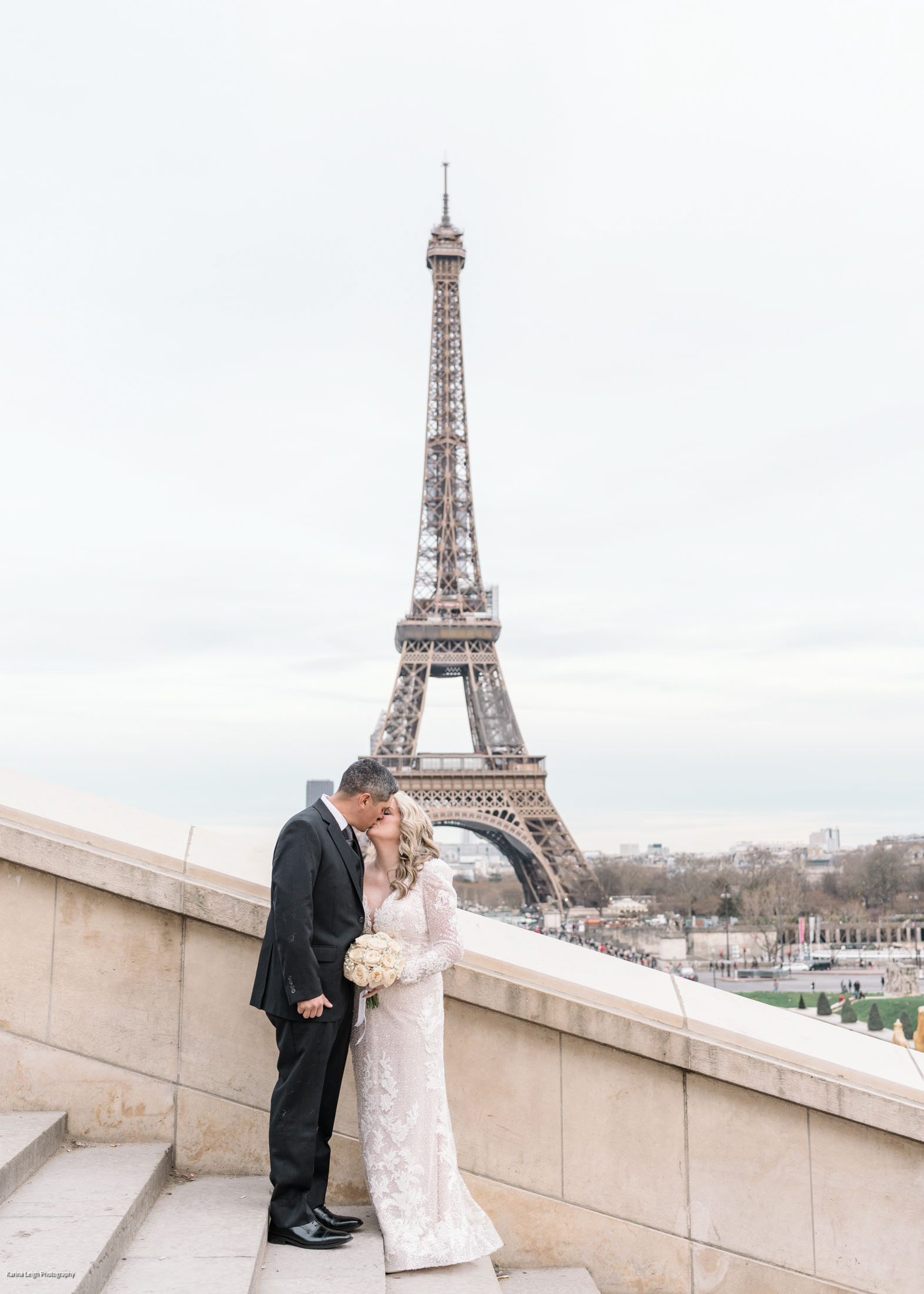 bride and groom kiss on staircase with view of eiffel tower in paris