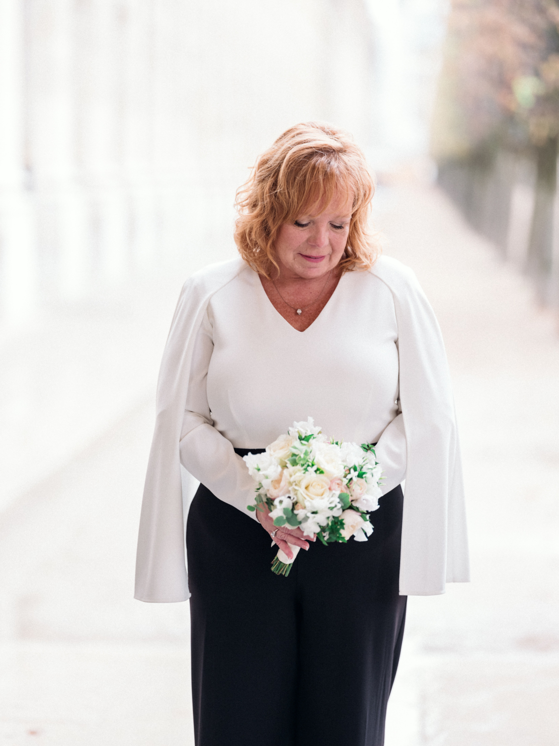 mature bride looks at her bouquet in paris france on her wedding day