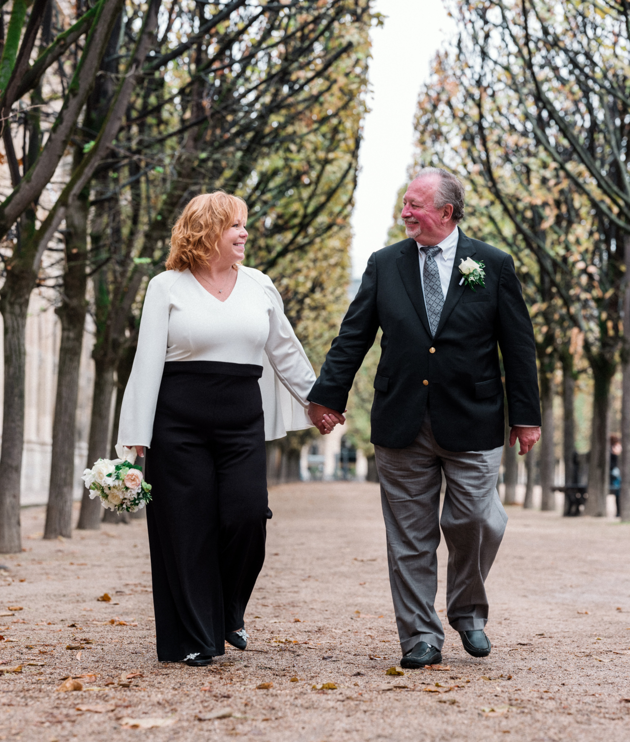 mature couple walk in the palais royal gardens on their wedding day in paris