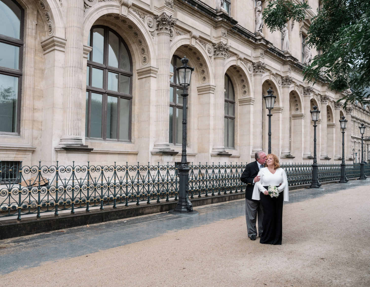 mature couple pose in front of louvre museum in paris on wedding day