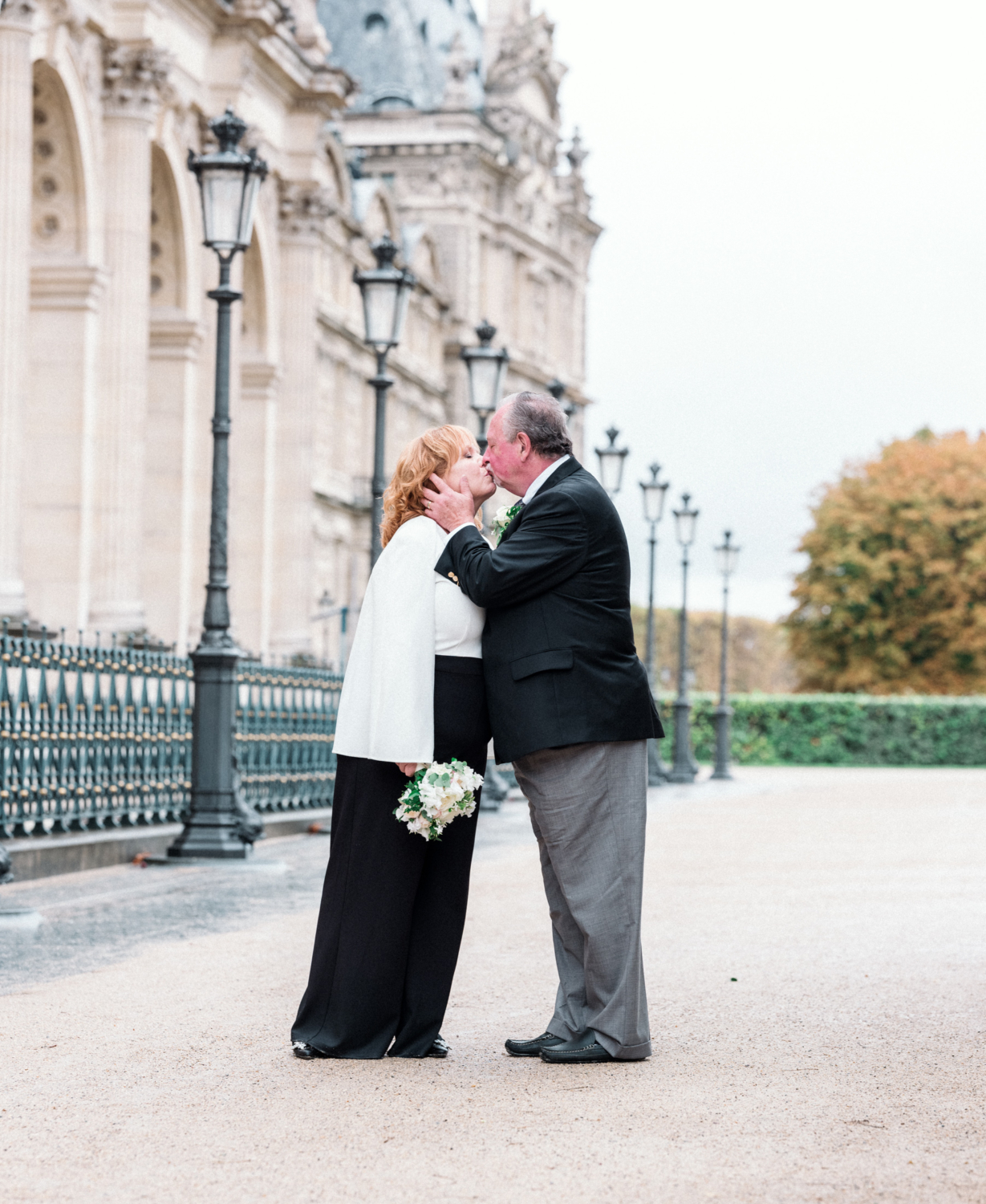 mature couple kiss on their wedding day in front of the louvre in paris