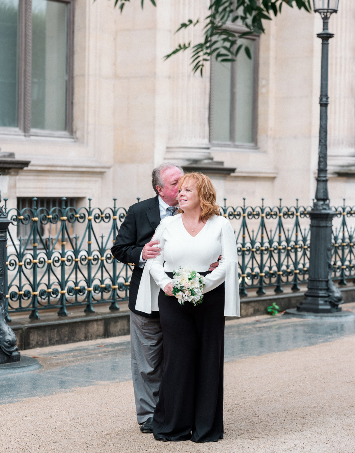 mature couple embrace in paris on their wedding day in front of the louvre museum