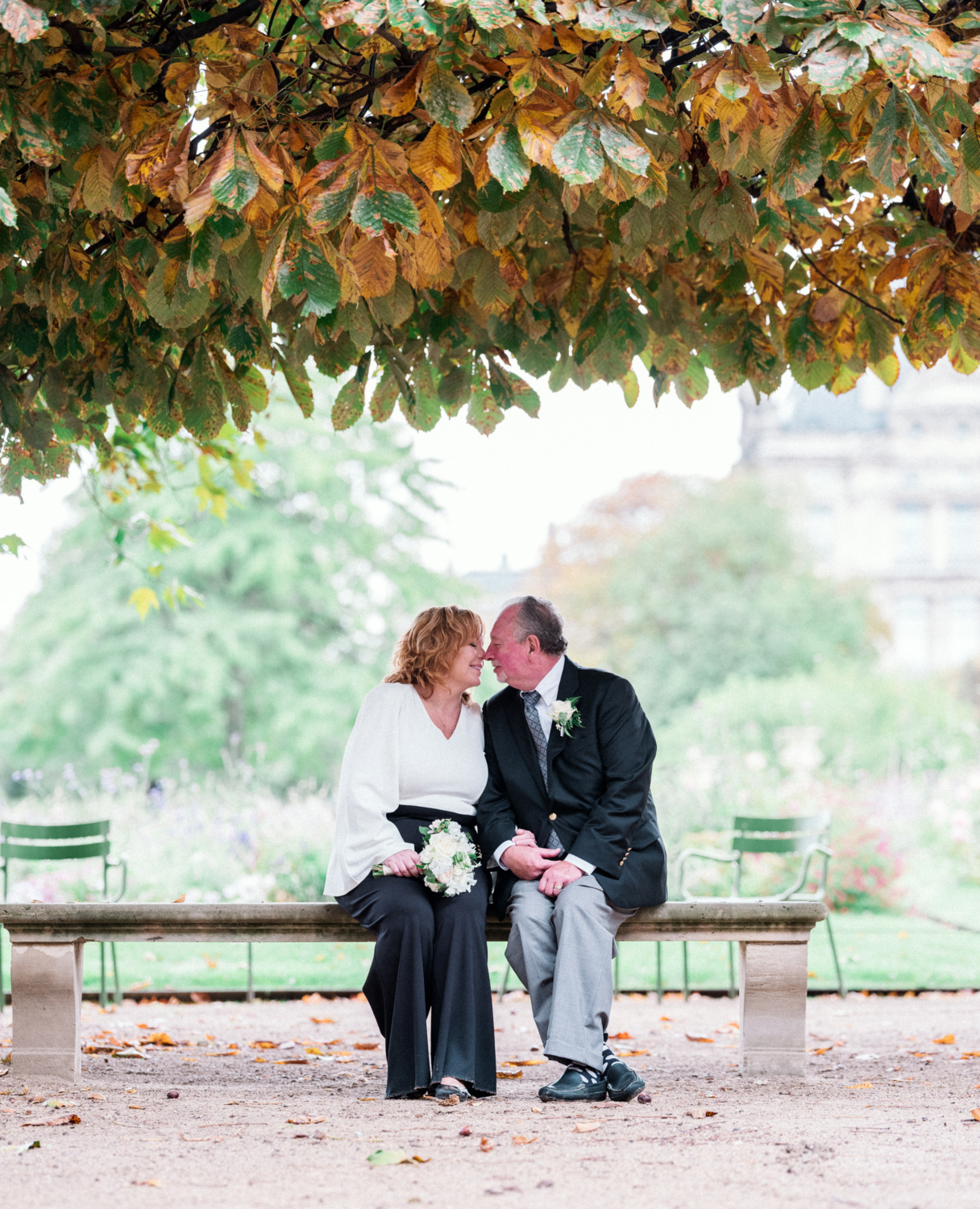 mature couple touch noses in tuileries garden in paris on their wedding day