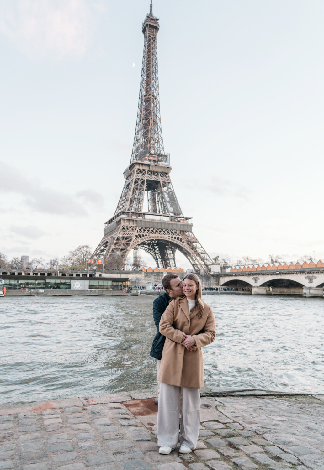 cute newly engaged couple embrace along river seine in paris