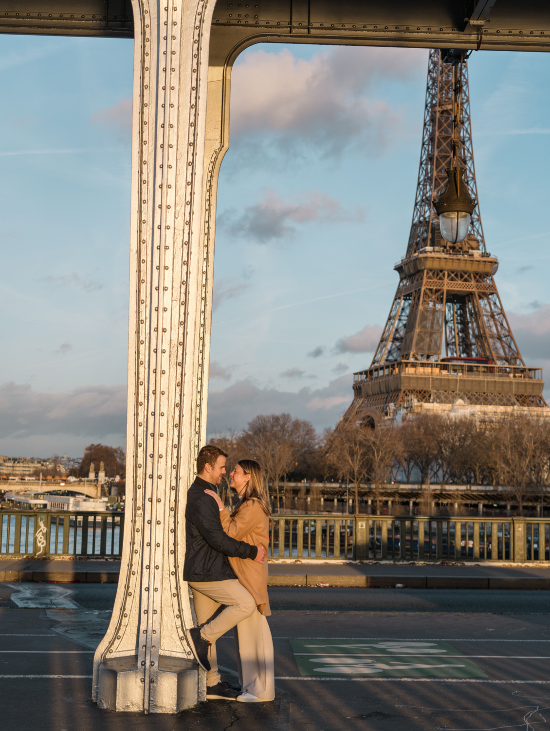 newly engaged couple embrace on bridge with eiffel tower view