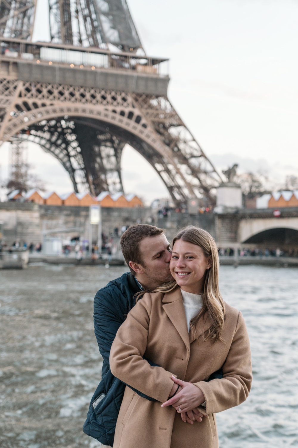 woman smiles as fiancé kisses her cheek in paris france