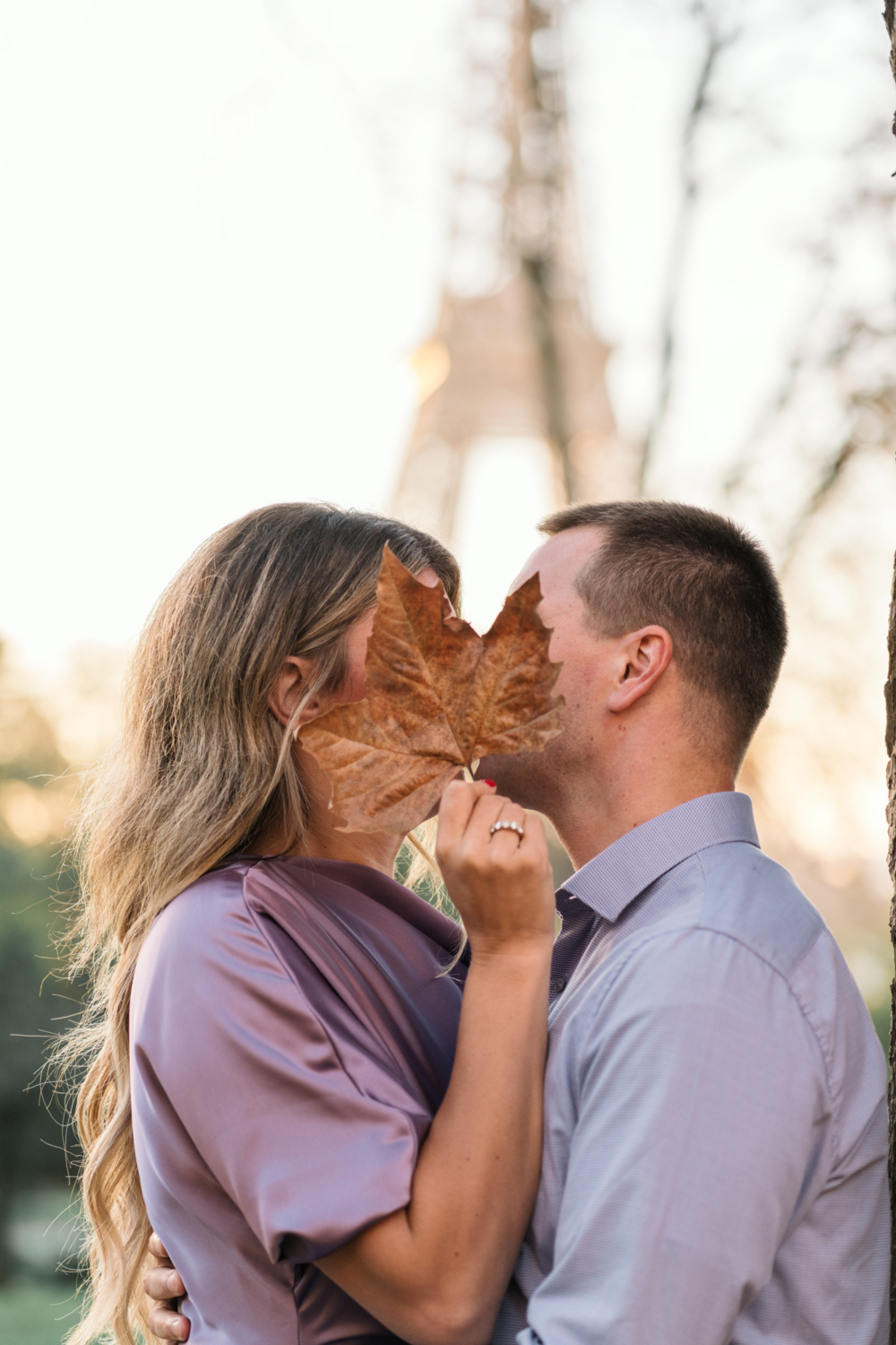 cute married couple kiss behind a leaf in autumn in paris