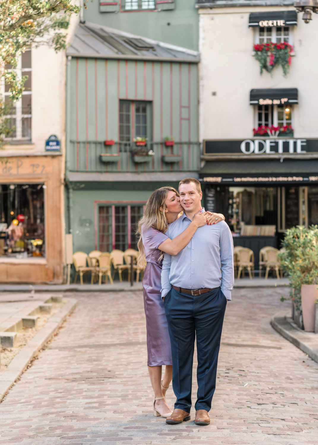 wife kisses husband on cheek outside odette restaurant in paris