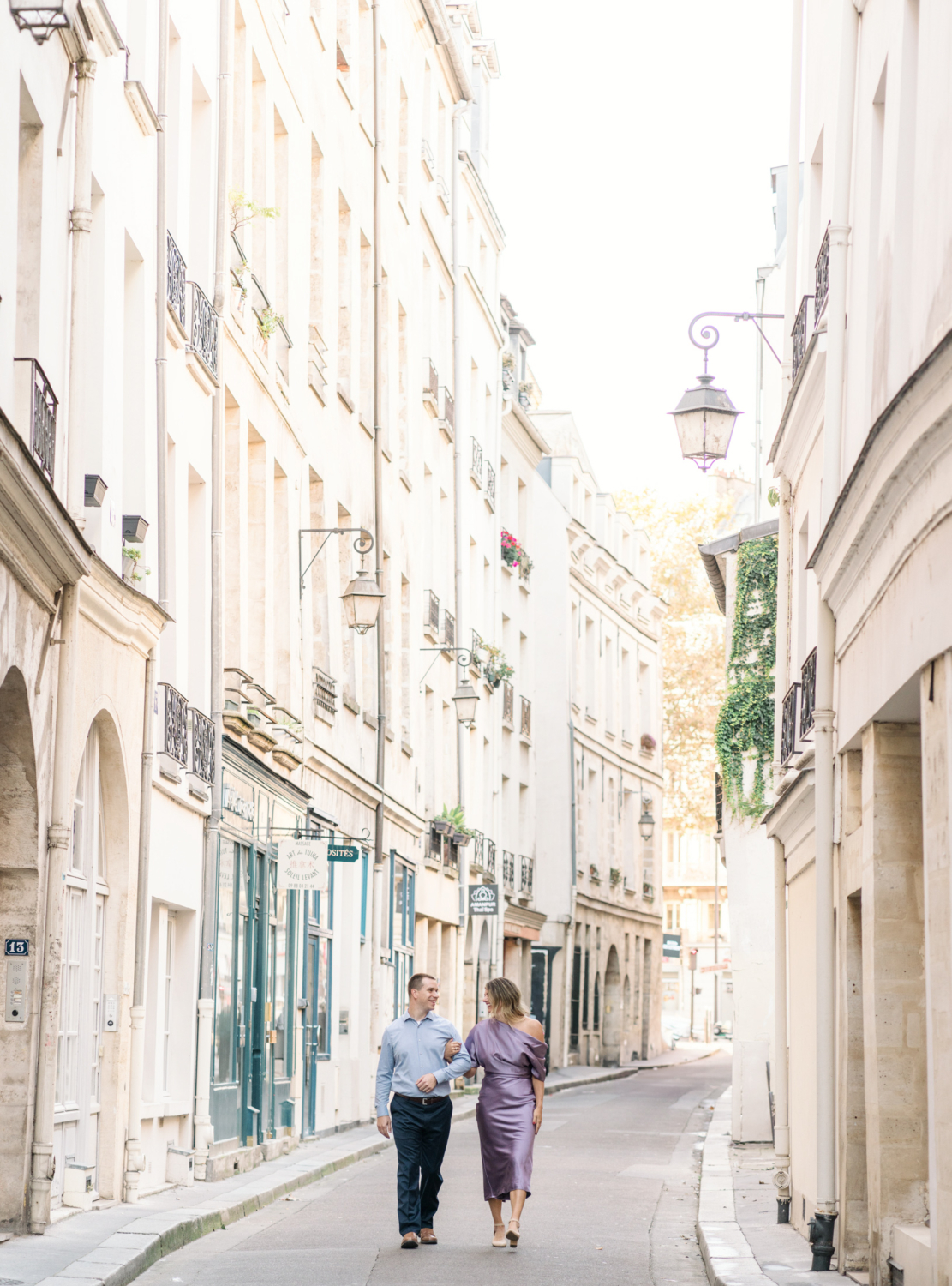 married couple walk arm in arm in charming paris neighborhood