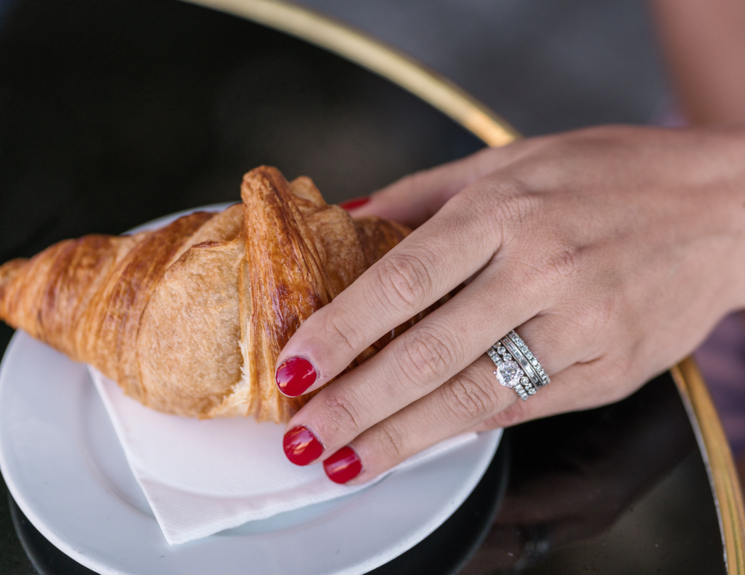 woman shows off her wedding ring with croissant in paris