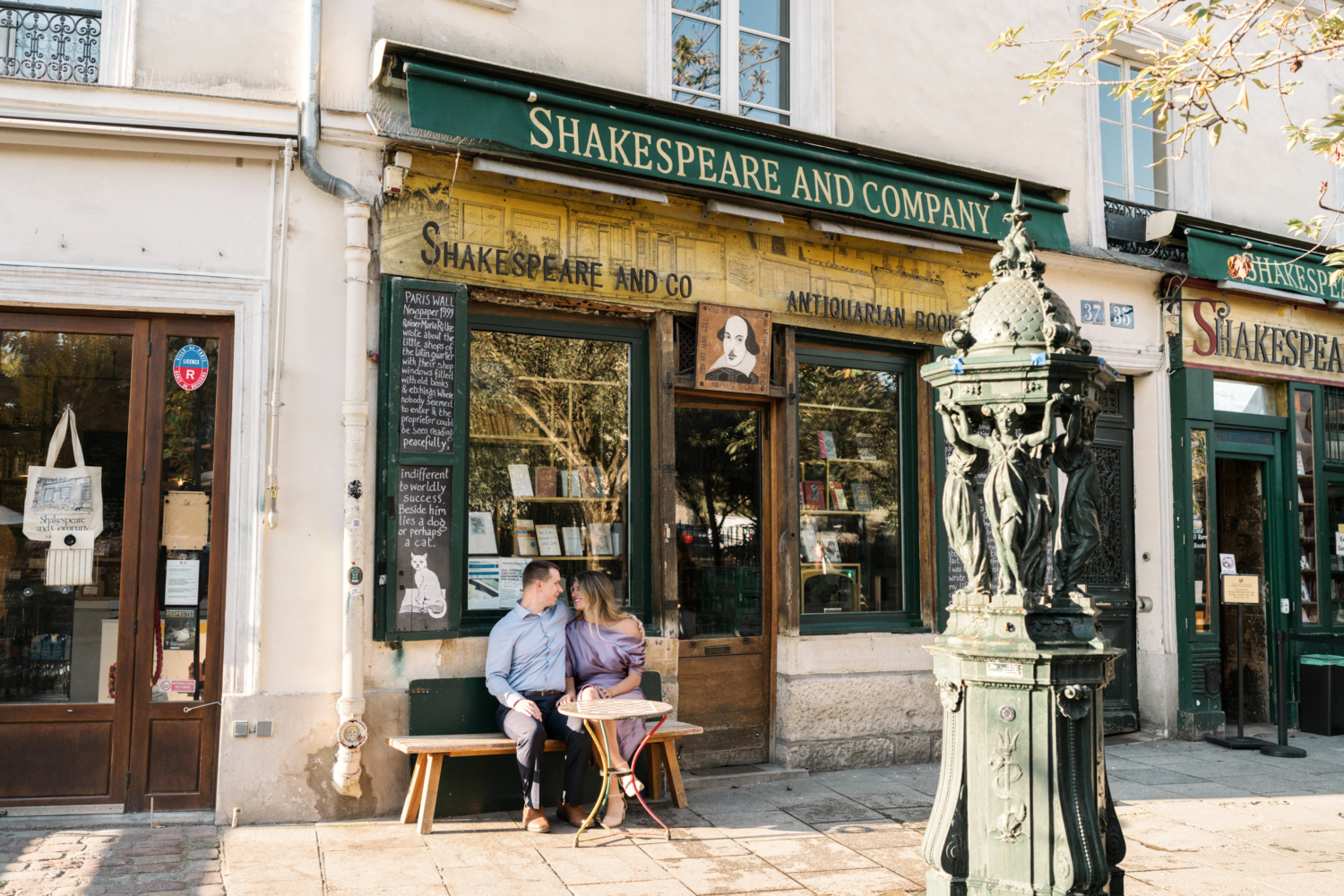 beautiful married couple sit in front of shakespeare and company bookstore in paris