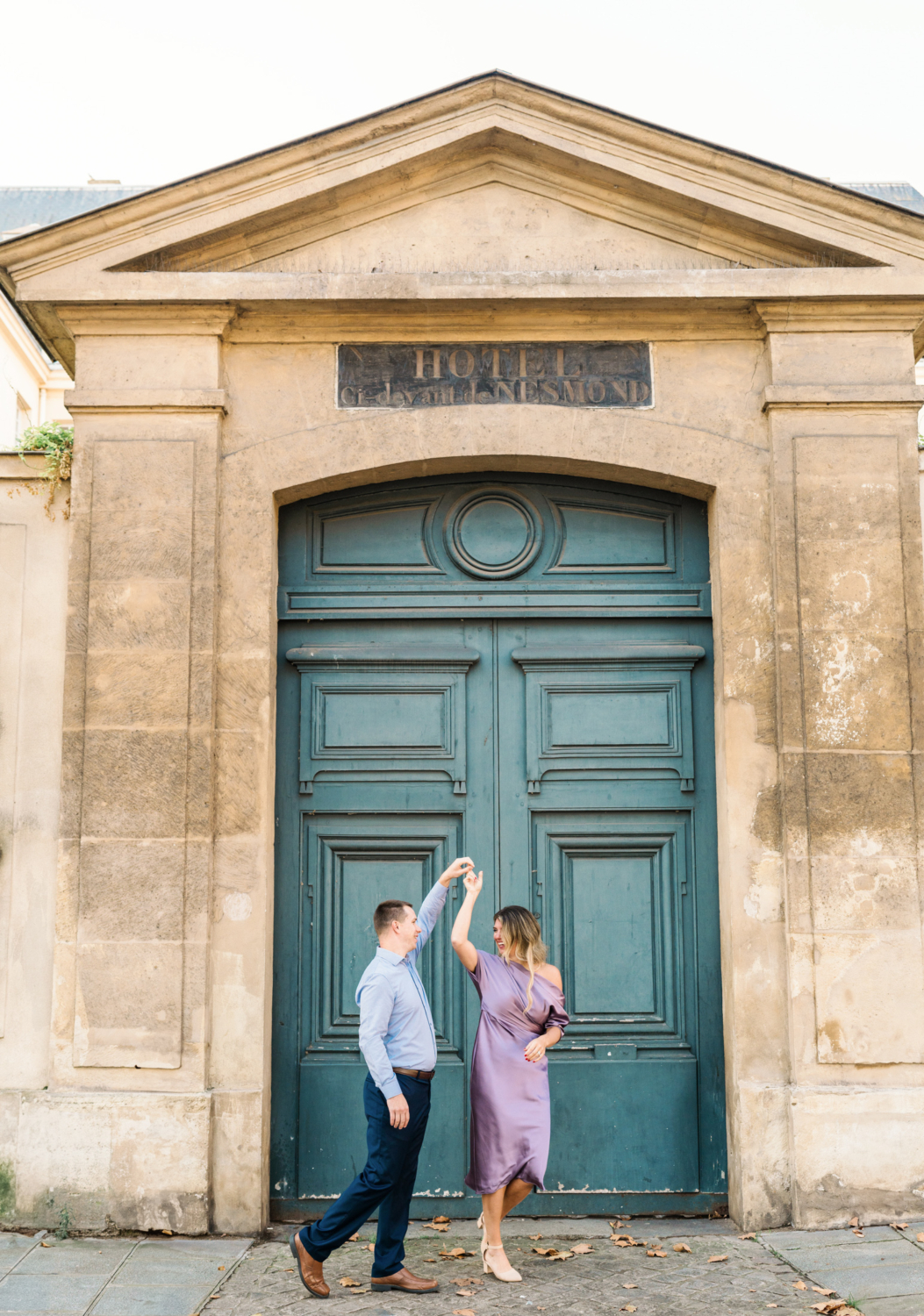 married couple dance in front of blue door in paris