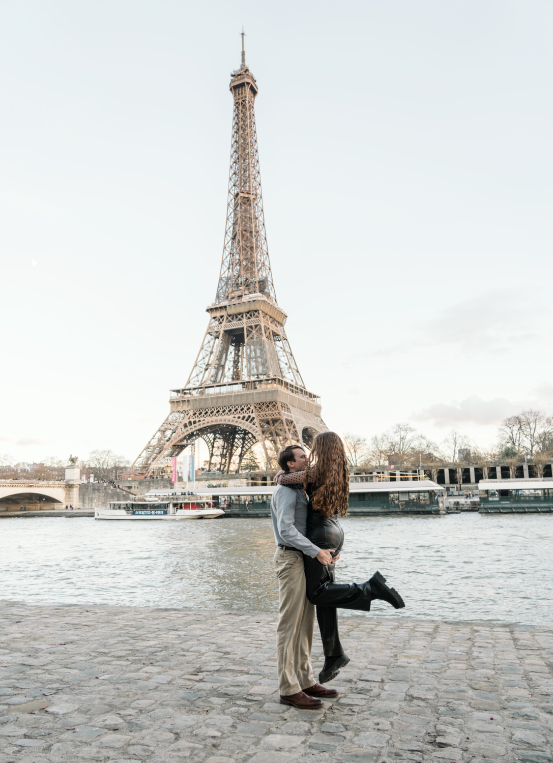 man lifts woman in joyful moment with view of eiffel tower