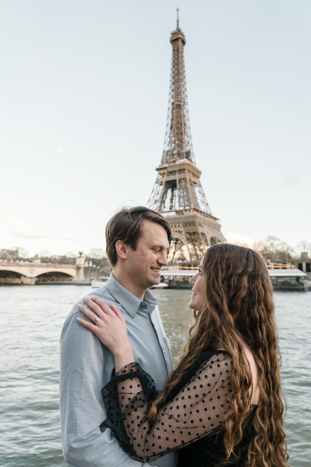 newly engaged couple smile at each other view of eiffel tower