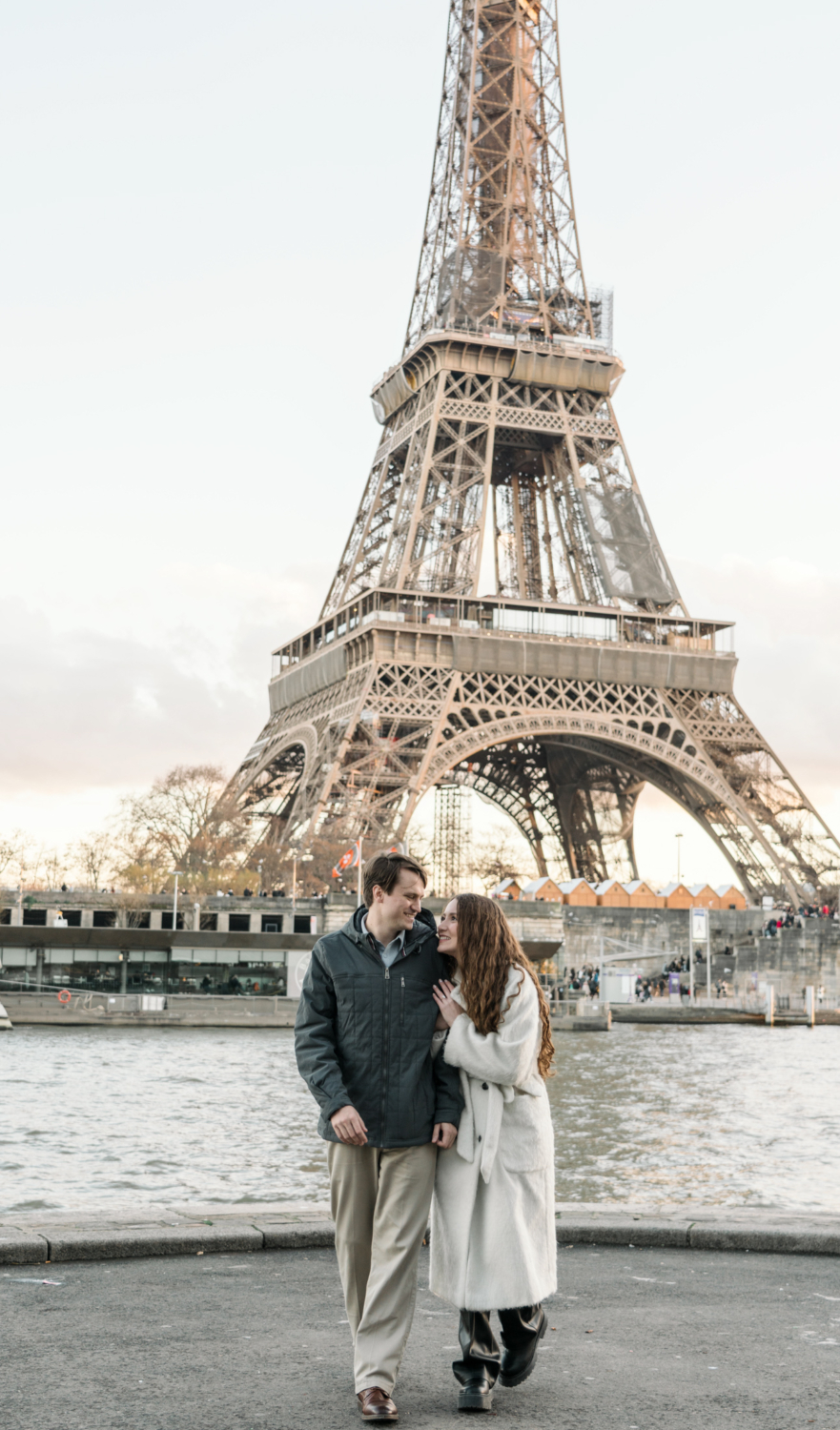 newly engaged couple walk together with view of eiffel tower in paris