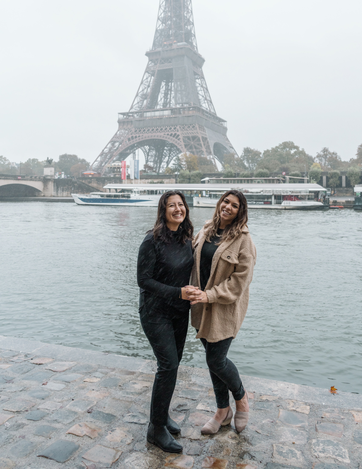 happy couple of two women smile after their engagement in the rain in paris france