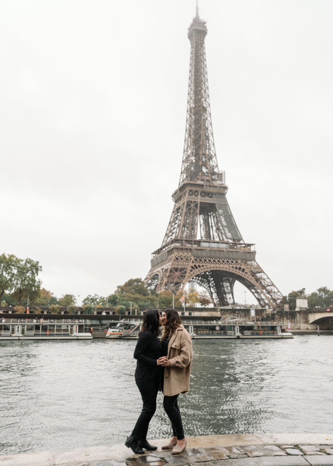 two women kiss with view of the eiffel tower in paris