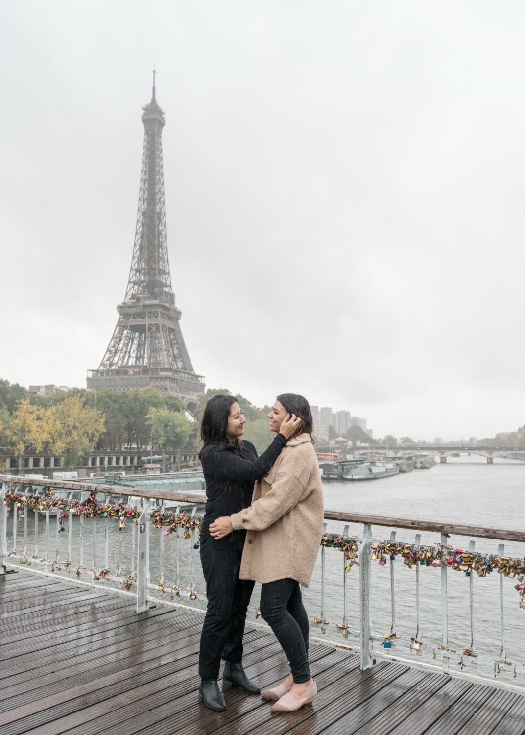 two women embrace with view of the eiffel tower during their engagement