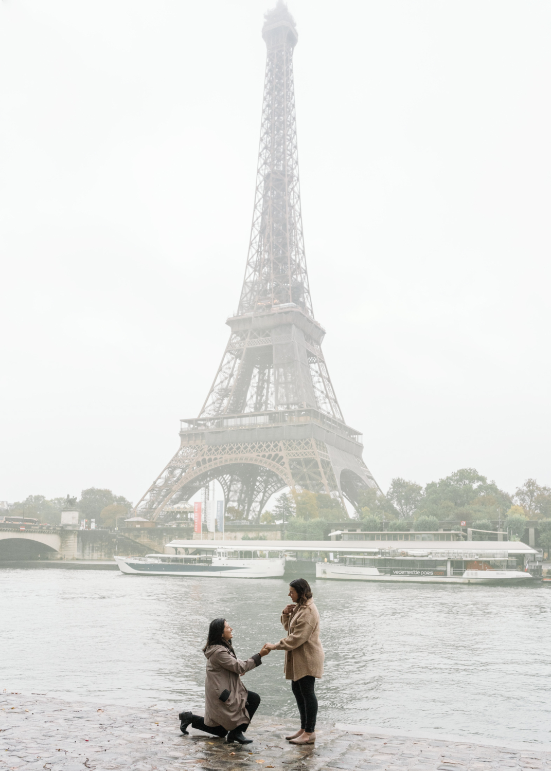 woman surprises girlfriend by proposing at the eiffel tower in the rain