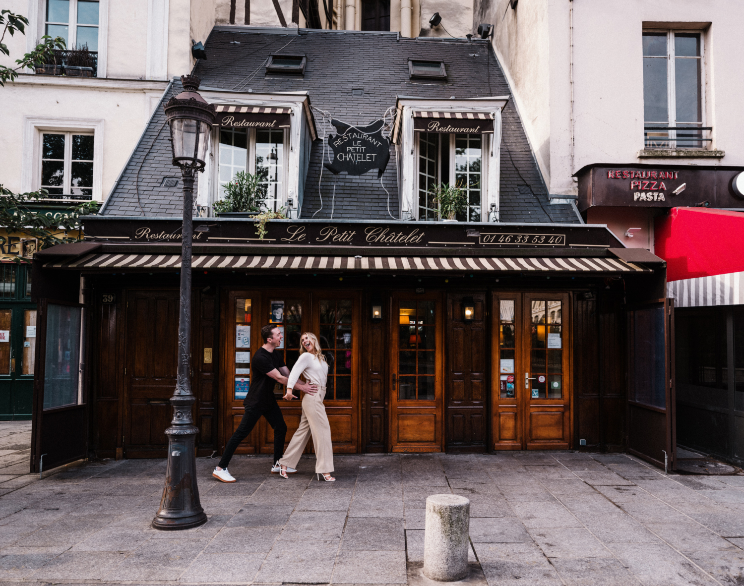 cute young newly engaged couple play run in front of a cafe in paris france