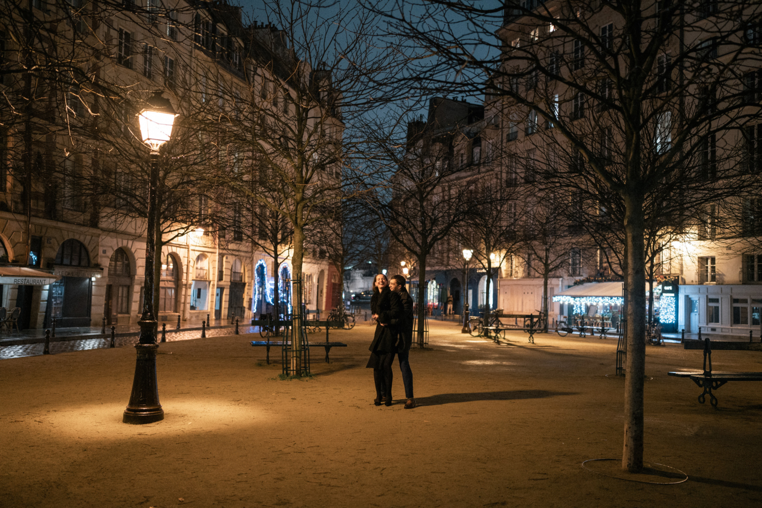 newly engaged couple play and laugh at place dauphine in paris