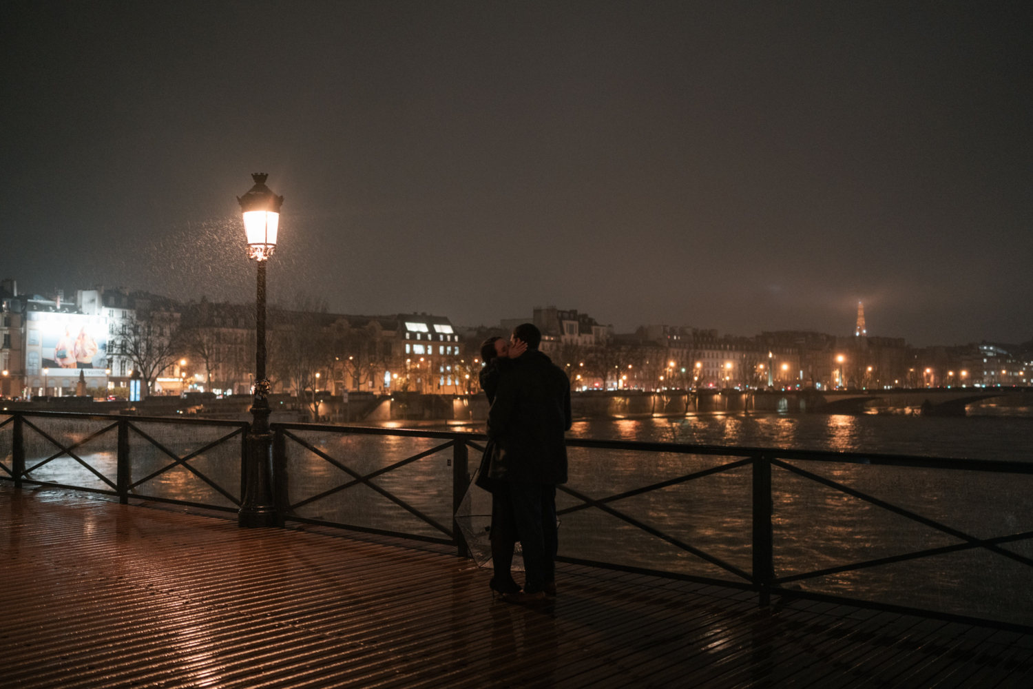 newly engaged couple kiss passionately on the pont des arts in paris at night