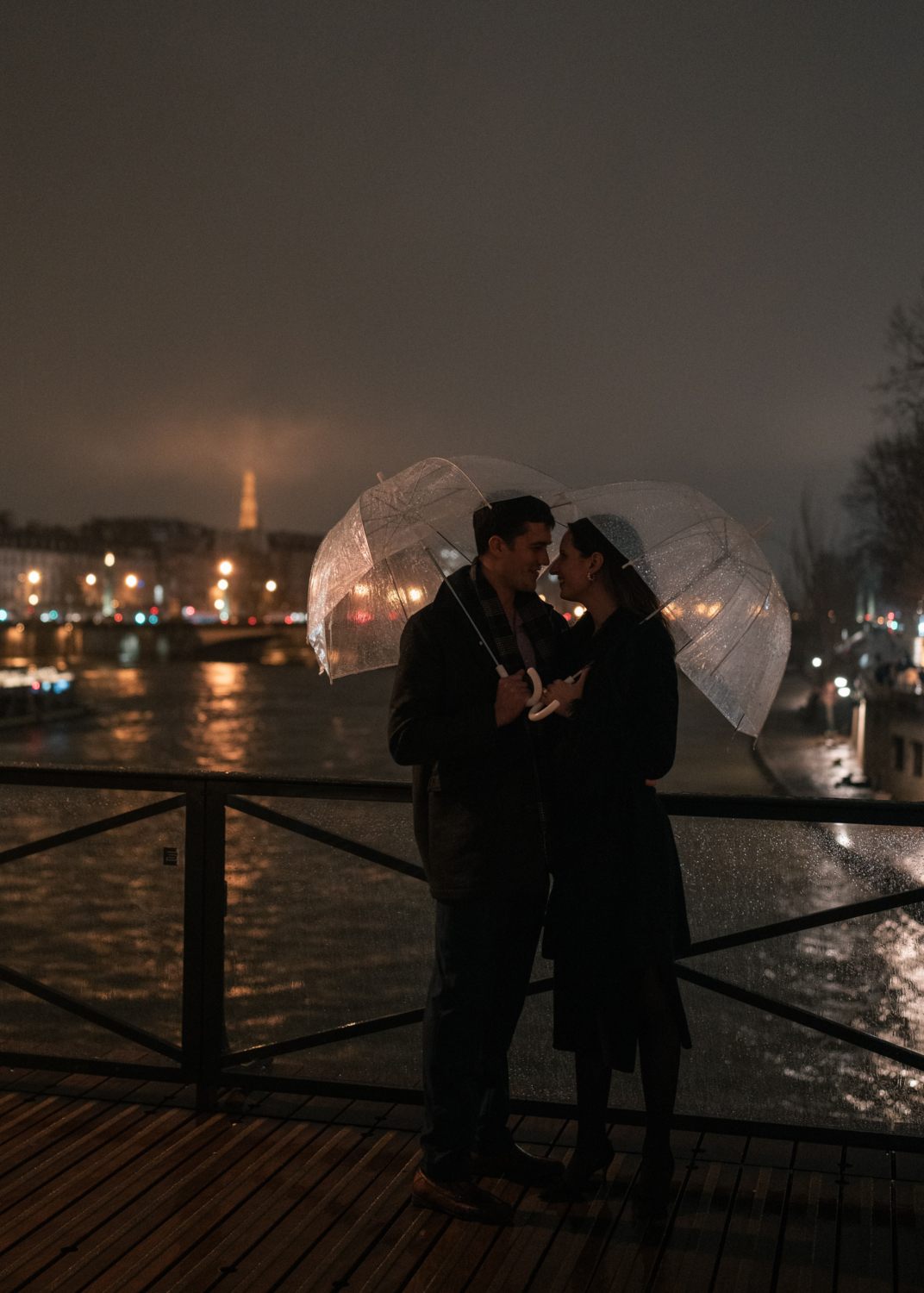 newly engaged couple smile at each other on bridge at night in paris