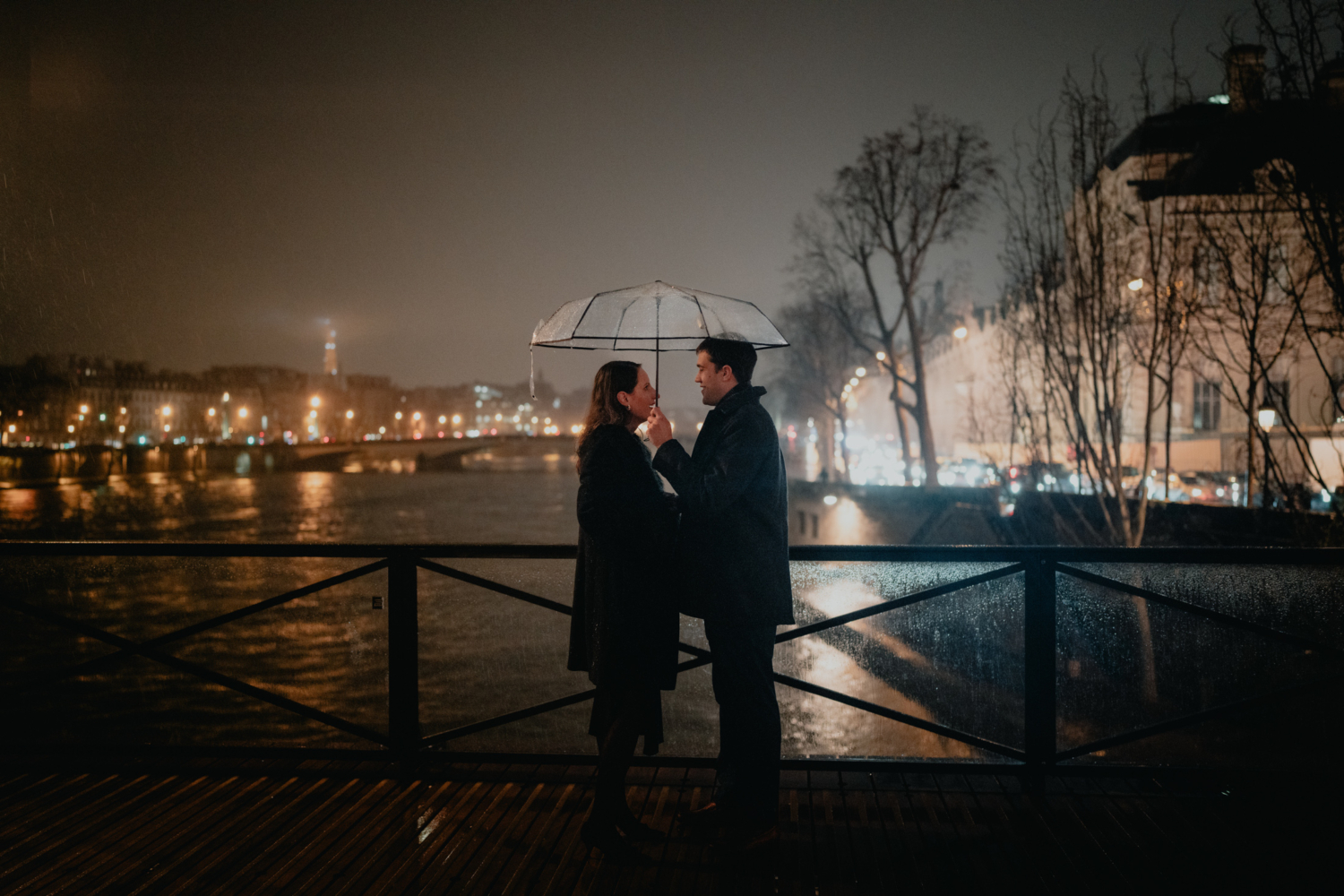 man stops to talk to woman on bridge at night in paris in the rain