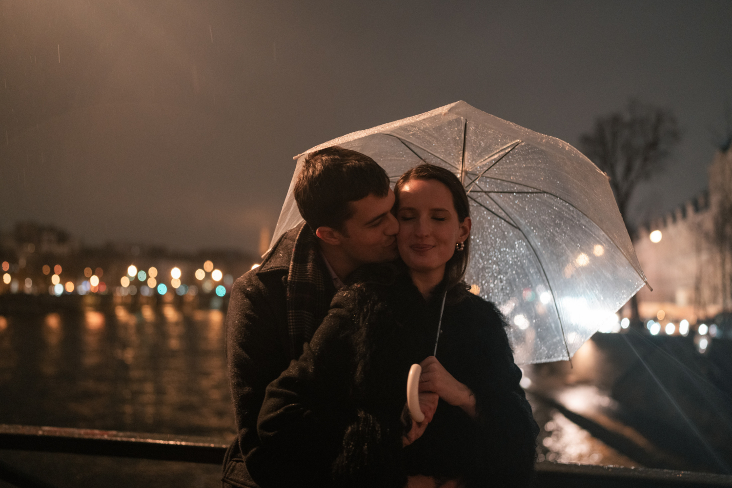 newly engaged couple embrace in the rain in paris at night