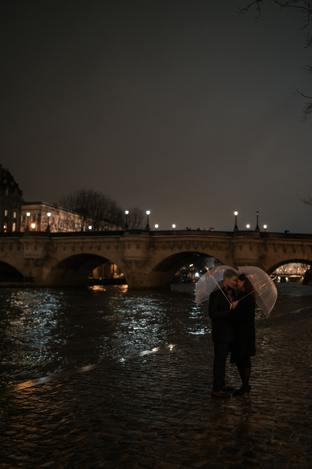 newly engaged couple hug in the rain in paris france at night