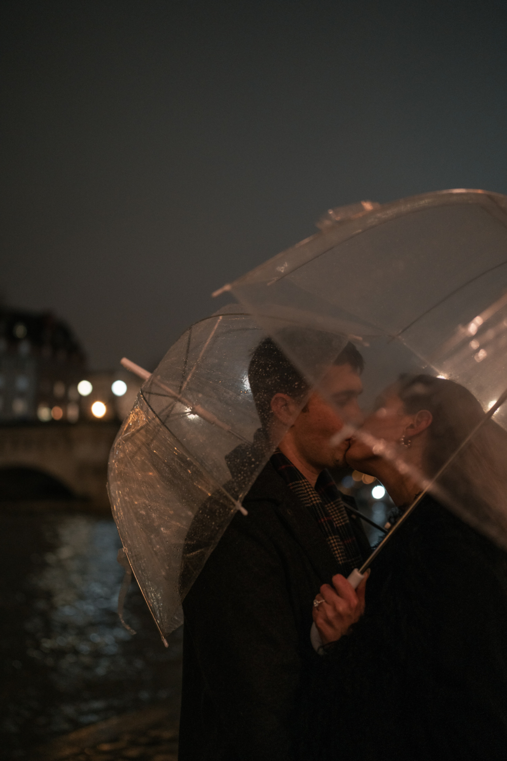 newly engaged couple kiss passionately under umbrella in paris france